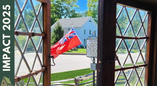 Peak House window taken from the inside, looking out towards front yard with flag